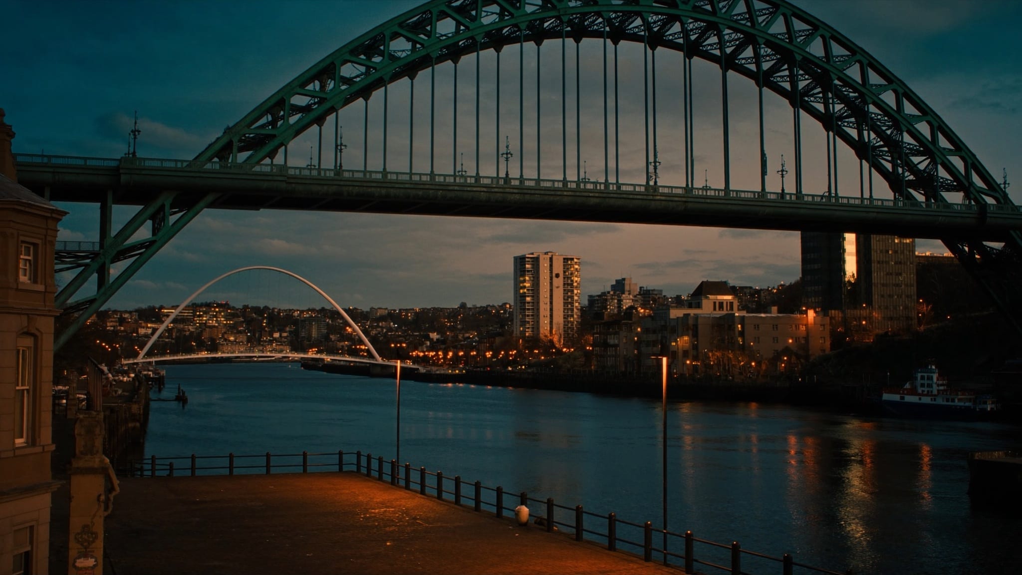 The Tyne Bridge arching over the River Tyne at dusk, with the Millennium Bridge and Newcastle Quayside behind